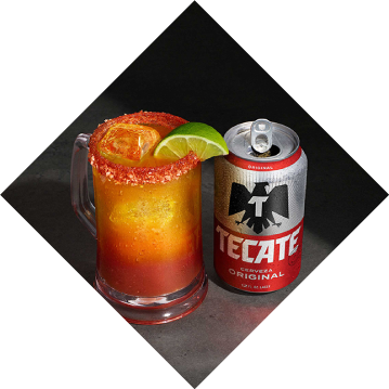 A mug of mixed Tecate® Original with clam juice, a lime and ice.
