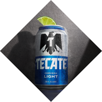 Open can of Tecate® Light with salt on the rim and two limes next to it.