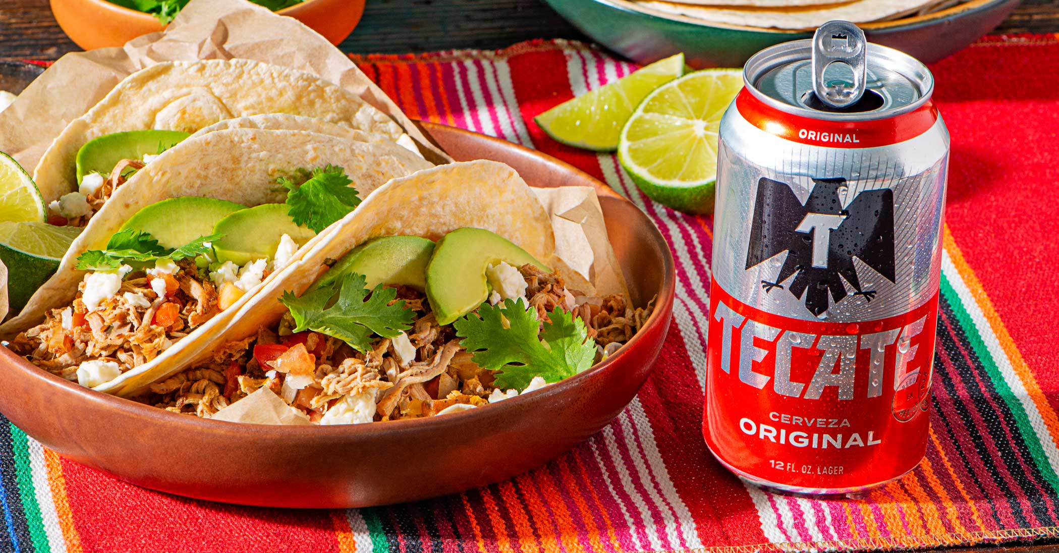 Tecate® Original and Tecate® Light cans with a lime, salt and some hot sauce on top.