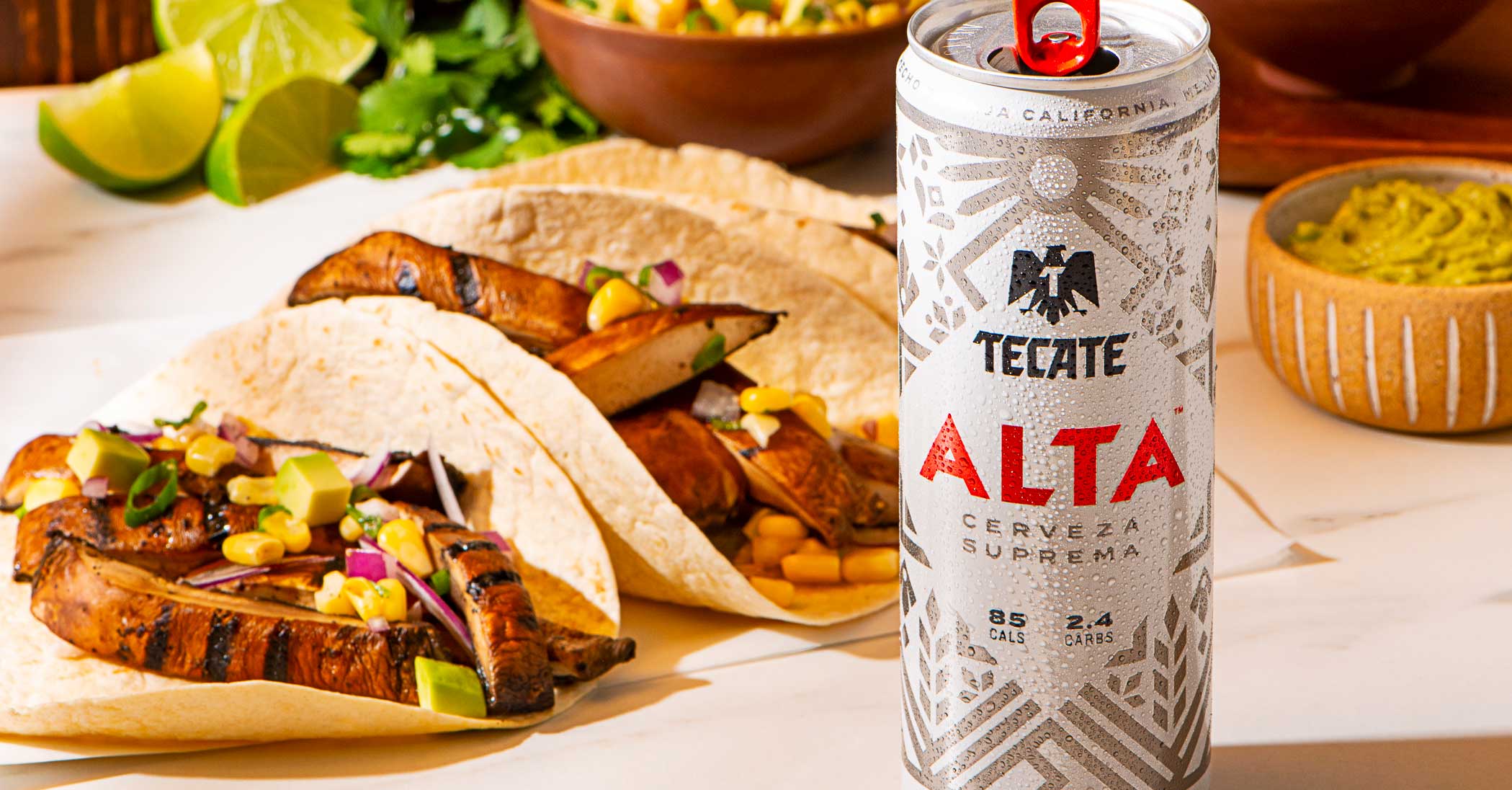 Tecate® Original and Tecate® Light cans with a lime, salt and some hot sauce on top.